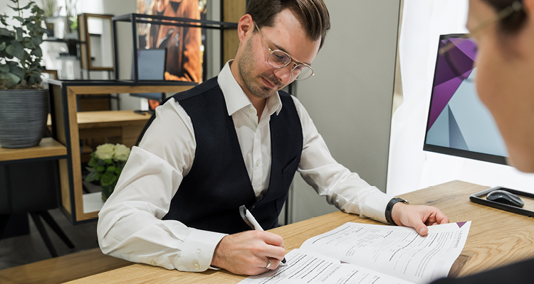 Kompetente Beratung bei Optik Osswald in Burgau – Mitarbeiter mit Brille beim Ausfüllen von Unterlagen für individuelle Sehlösungen und erstklassigen Kundenservice.