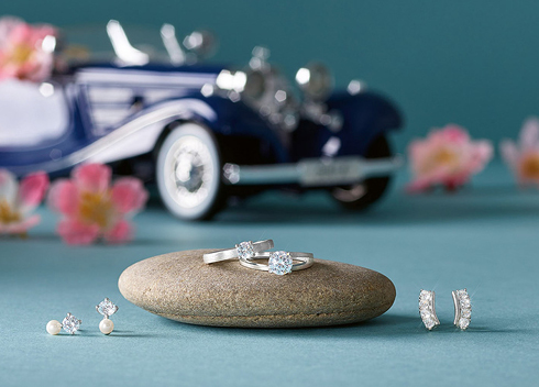 Edler Hochzeitsschmuck mit Diamantringen, Perlenohrsteckern und Ohrringen, arrangiert vor Oldtimer-Dekoration – exklusiv bei Optik und Schmuck Osswald in Burgau, Süddeutschland.