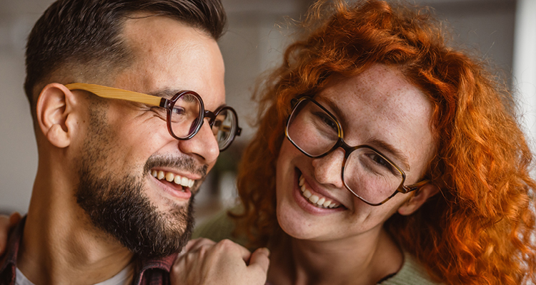 Zwei glückliche Menschen mit modernen Brillen lachen und schauen sich an – stilvolle Sehlösungen für Sie & Ihn bei Optik Osswald in Burgau.
